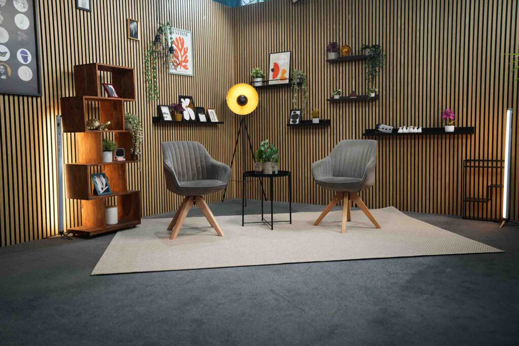 Livestream Studio München mit zwei Sesseln, Holzlamellenwand und professioneller Beleuchtung für Interviews, Podcasts und Webinare.